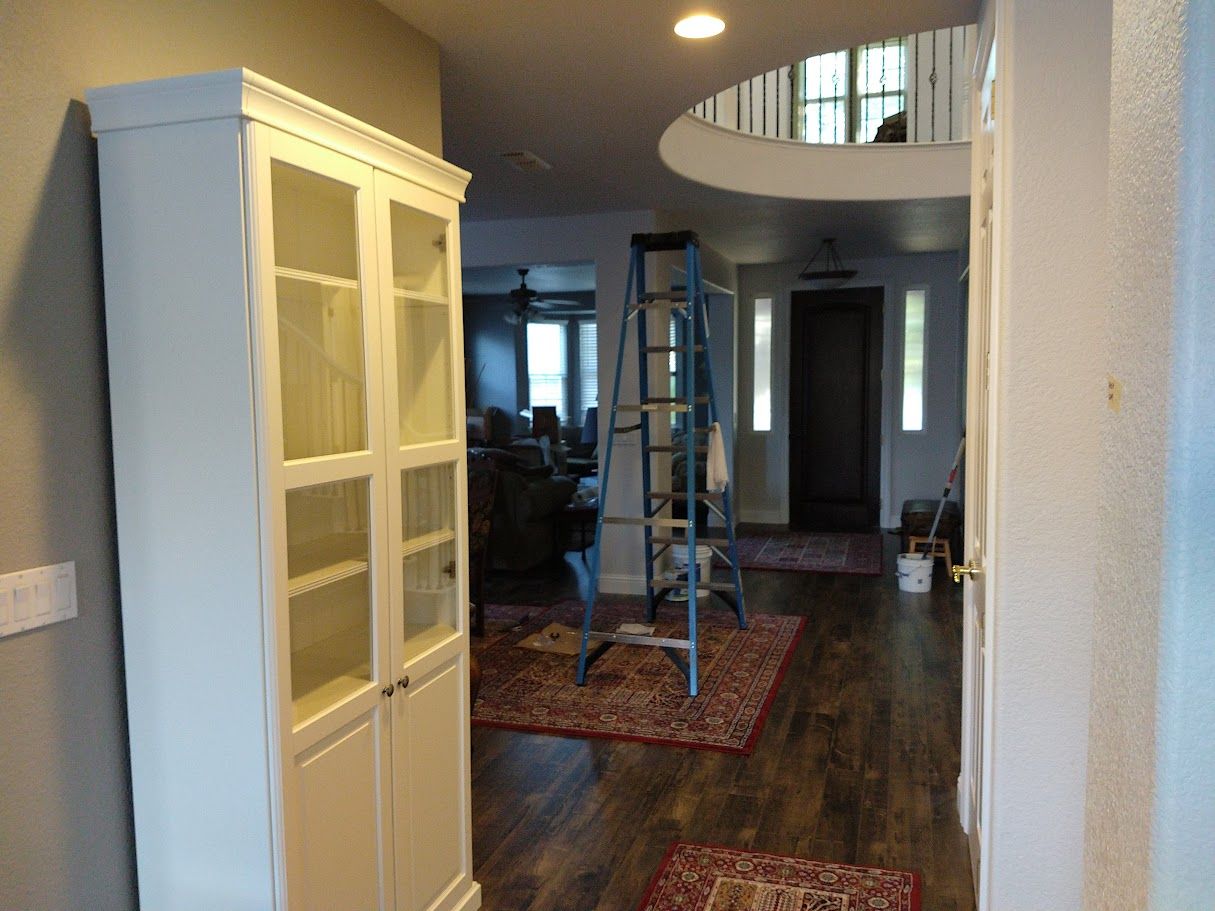Modern two-story townhouse with white and gray exterior, glass balconies, & black window coverings against a clear blue sky.
