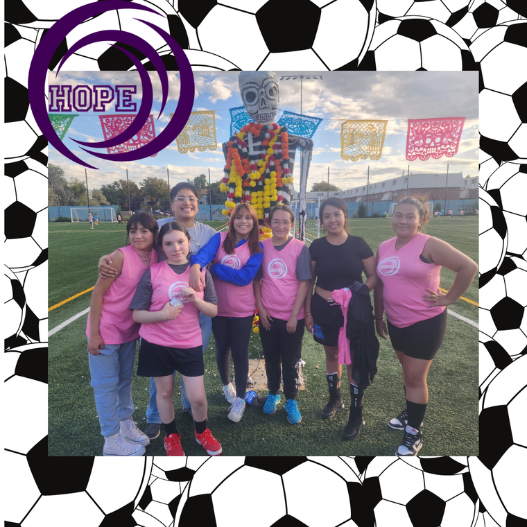 A group of people are posing for a picture on a soccer field.