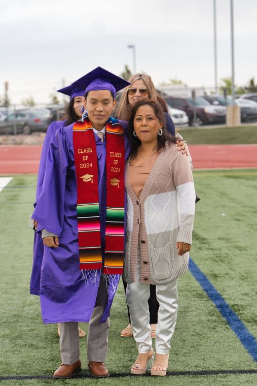 A man in a purple cap and gown is standing next to a woman on a field.