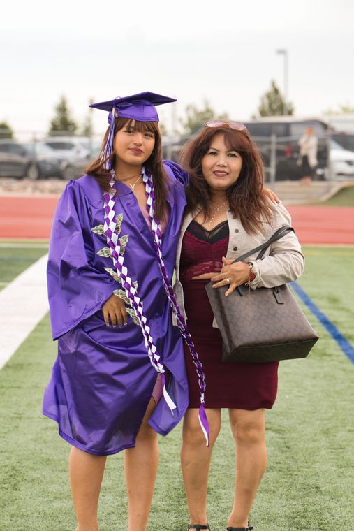 A woman in a purple graduation cap and gown is standing next to a woman in a red dress.