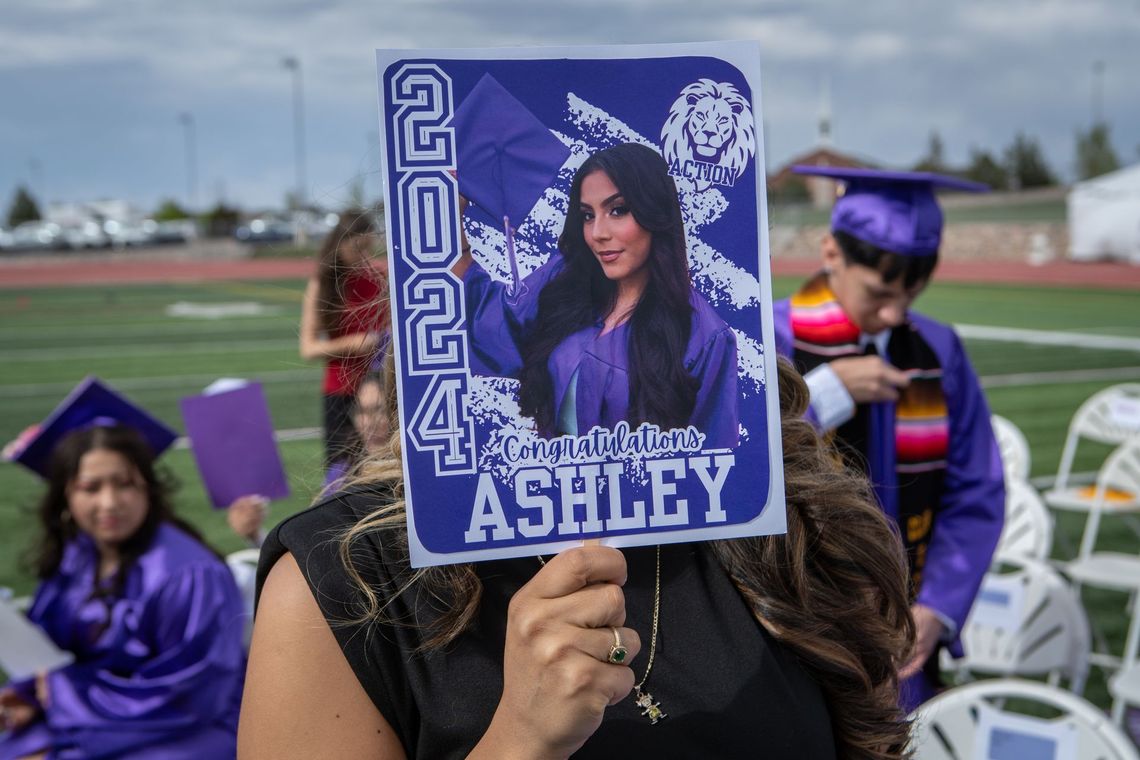 A woman is holding a picture of a graduate in front of her face.