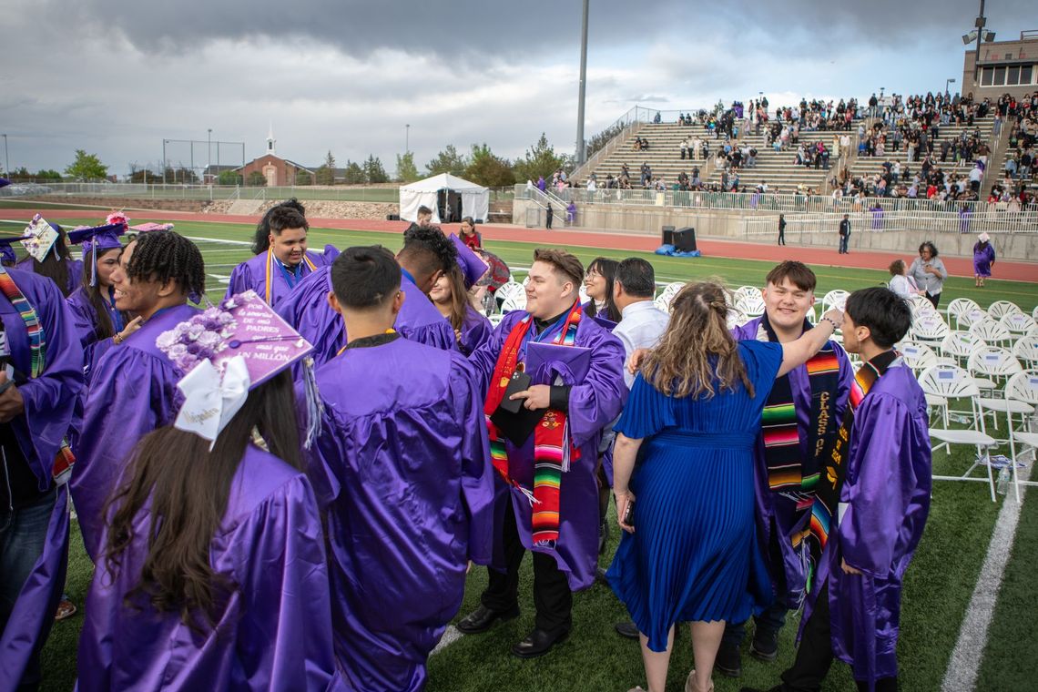 A group of graduates in purple gowns are standing on a field.