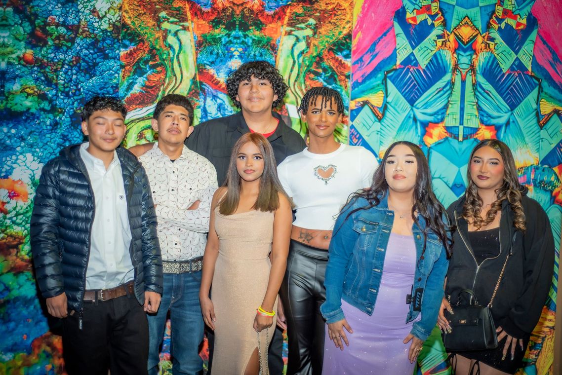 A group of people are posing for a picture in front of a colorful wall.