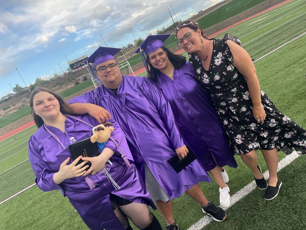 A group of graduates are posing for a picture on a field.