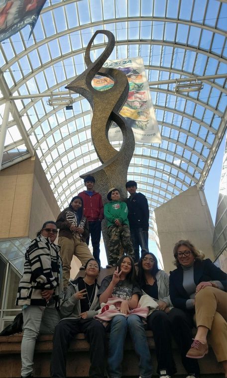 A group of people are posing for a picture in front of a sculpture.