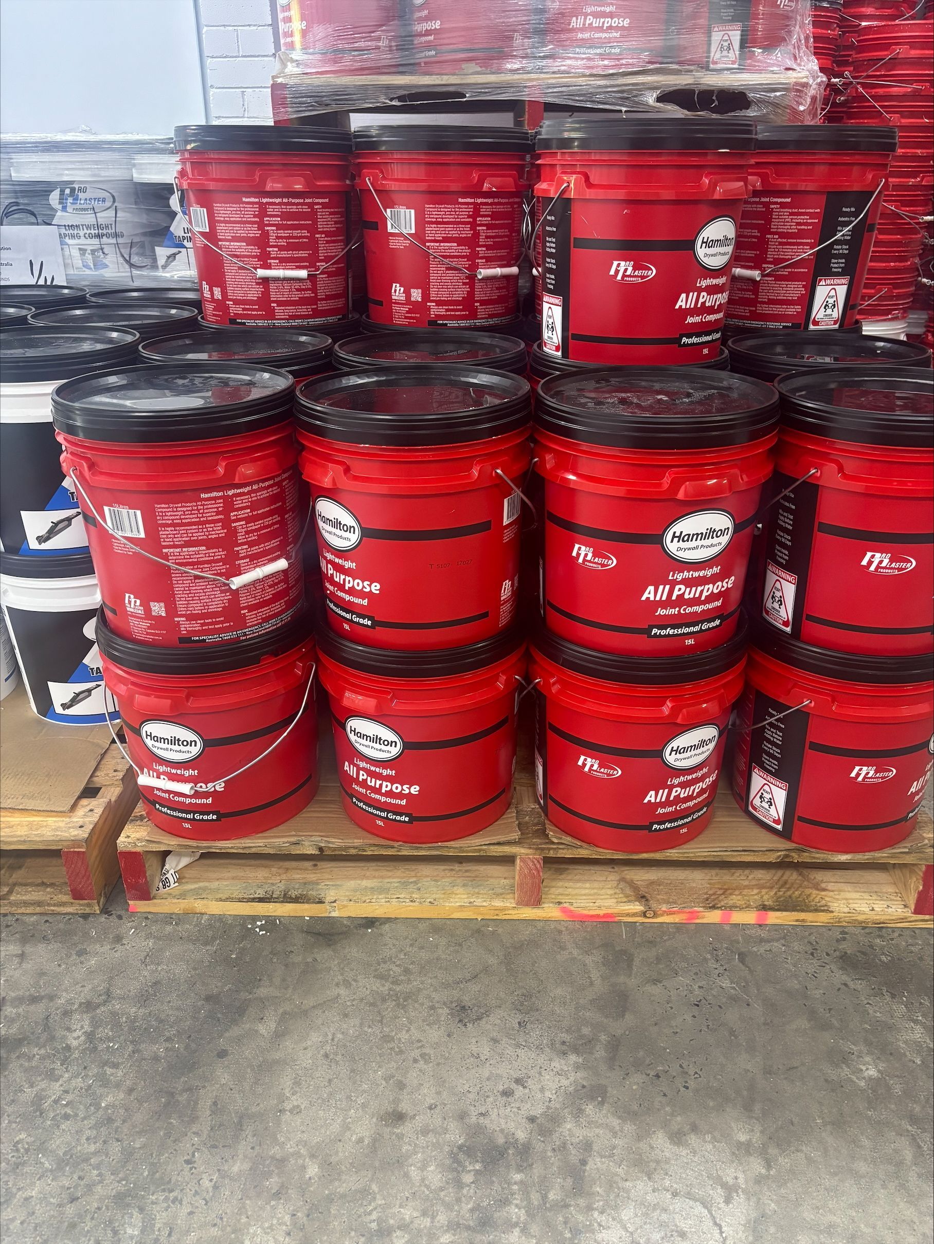 A Stack Of Red Plaster In Buckets On A Wooden Pallet — North Coast Plaster Solutions in Lismore, NSW