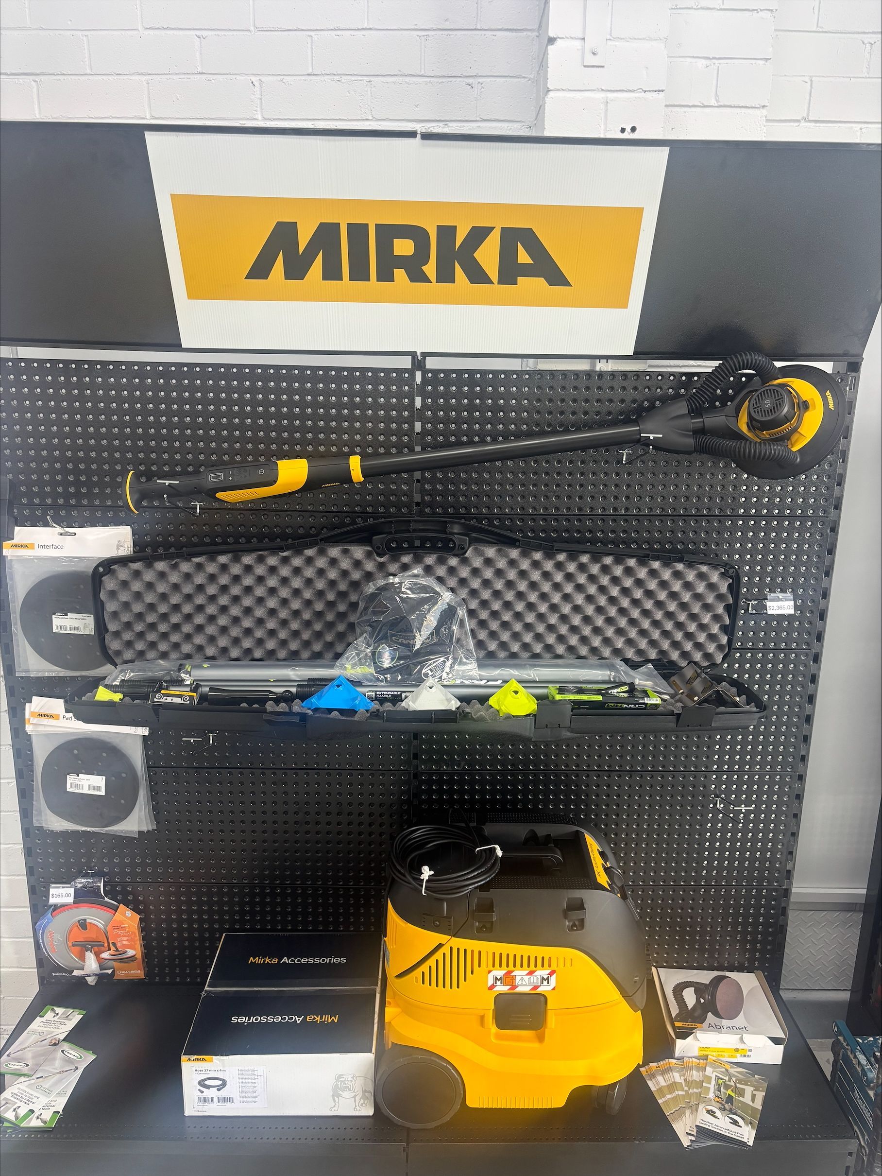 A Man is Kneeling Down and Painting a Wall With a Brush — North Coast Plaster Solutions in Lismore, NSW