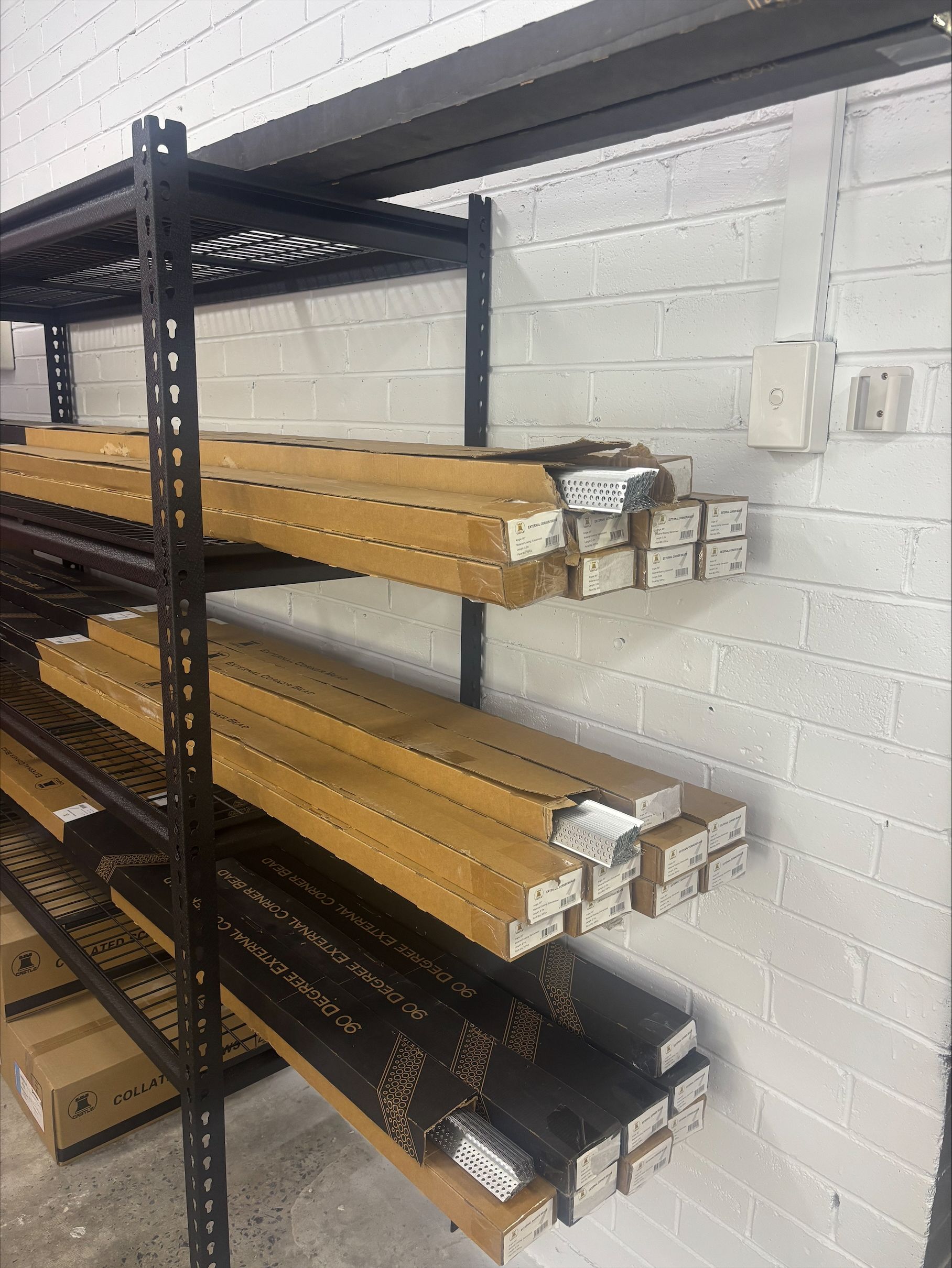 Long Pieces Of Iron Sitting On A Black Shelf In Cardboard Boxes— North Coast Plaster Solutions in Lismore, NSW