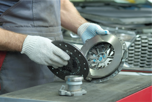 A man is holding a clutch disc in his hands.