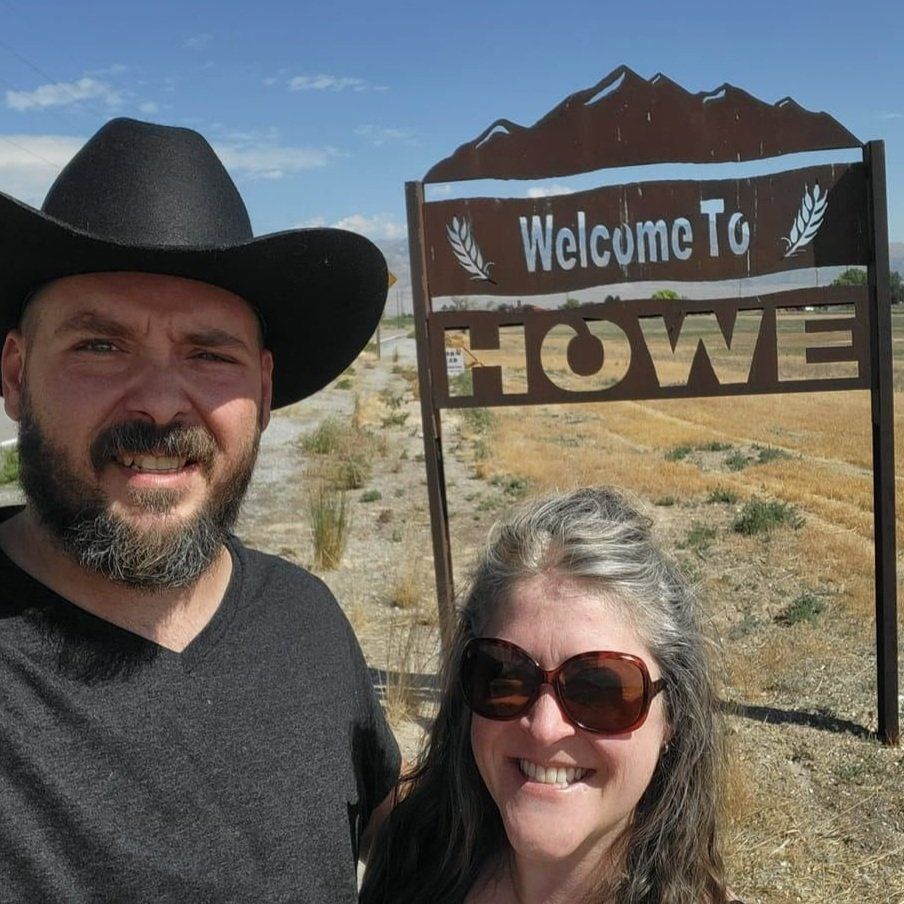 A man and woman standing in front of a sign that says welcome to howe