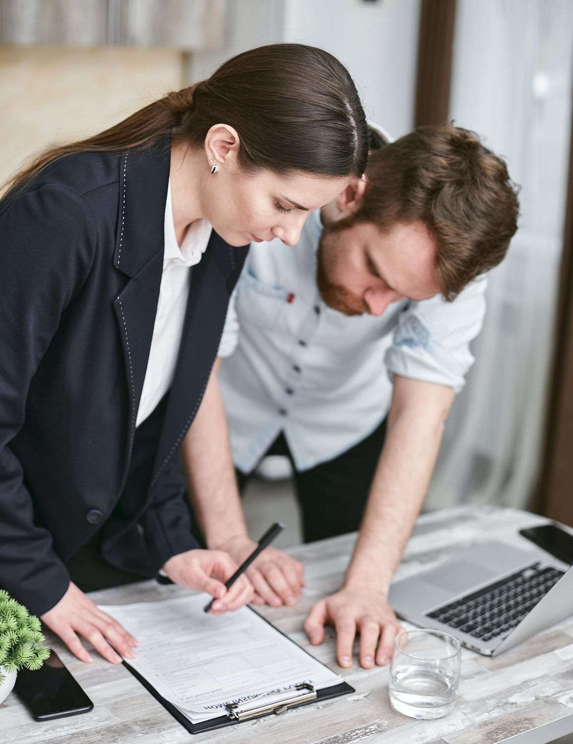 A man with a backpack is standing next to a lake in the woods.