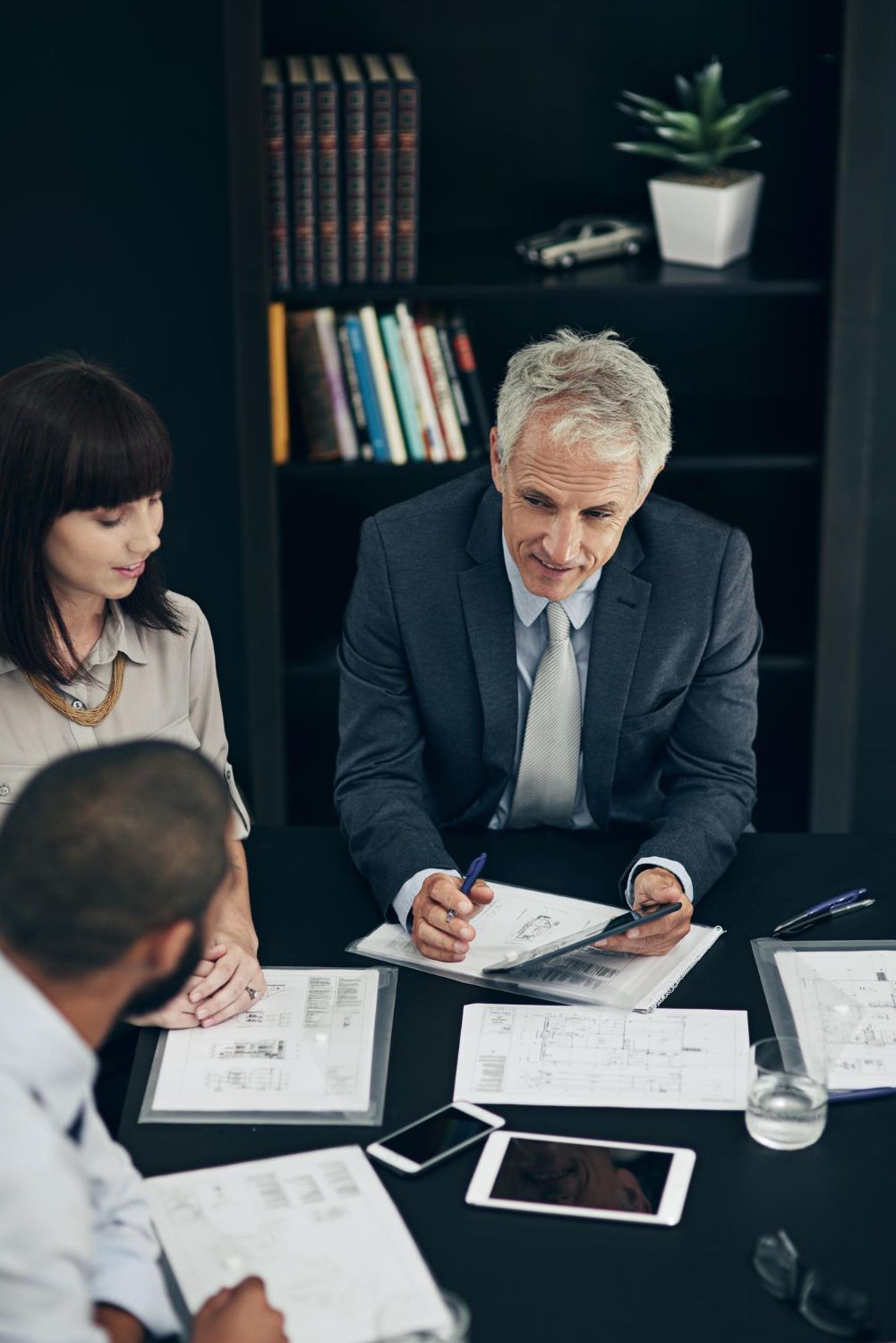 A man with a backpack is standing next to a lake in the woods.