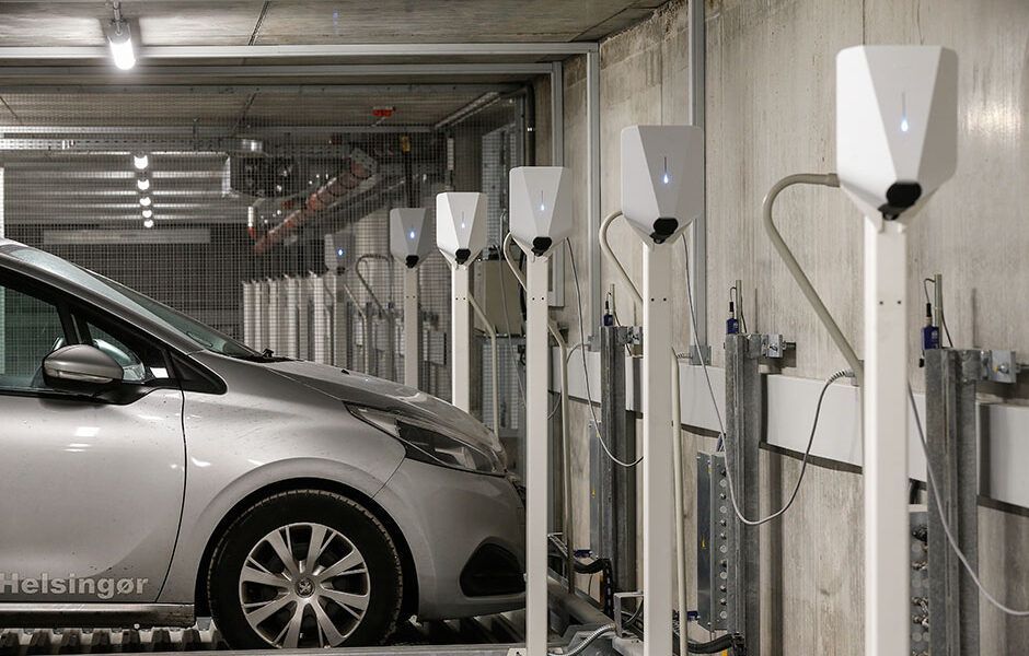 En sølvfarvet bil bliver ladet op i et parkeringshus.