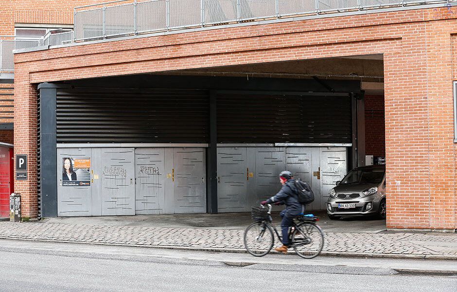 En mand cykler på fortovet foran en bygning.