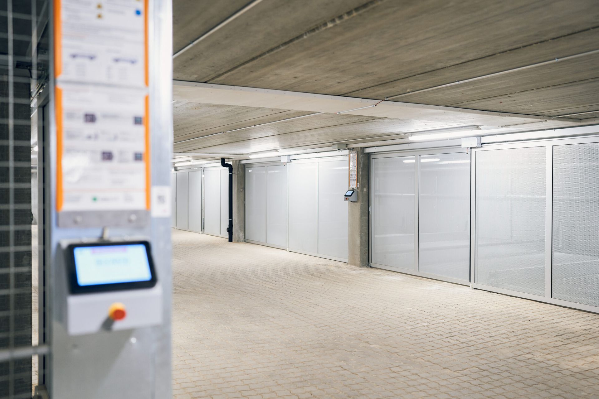 En lang gang i en bygning med touchskærm på væggen.