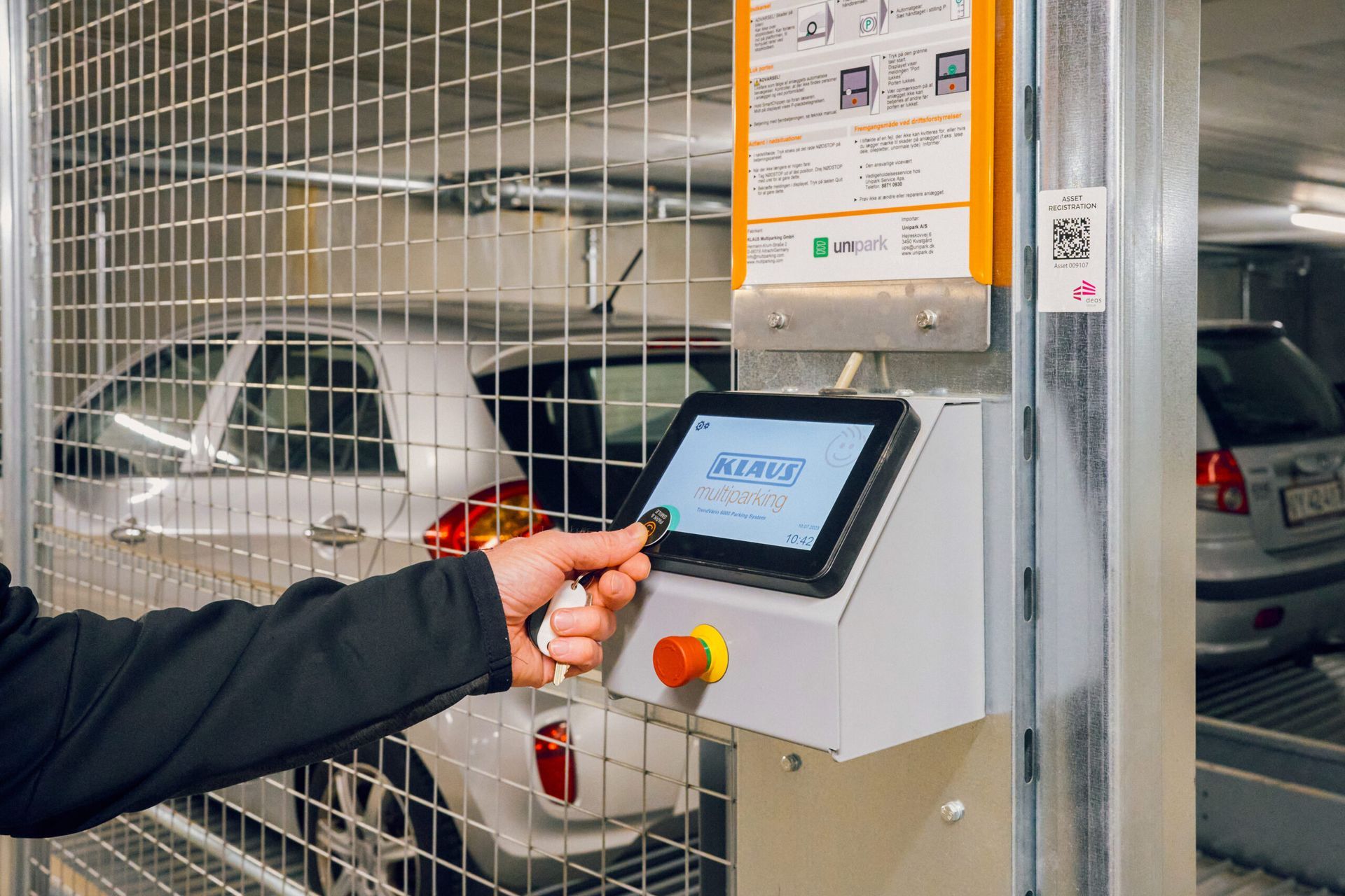 En person trykker på en knap på en maskine i en parkeringskælder.