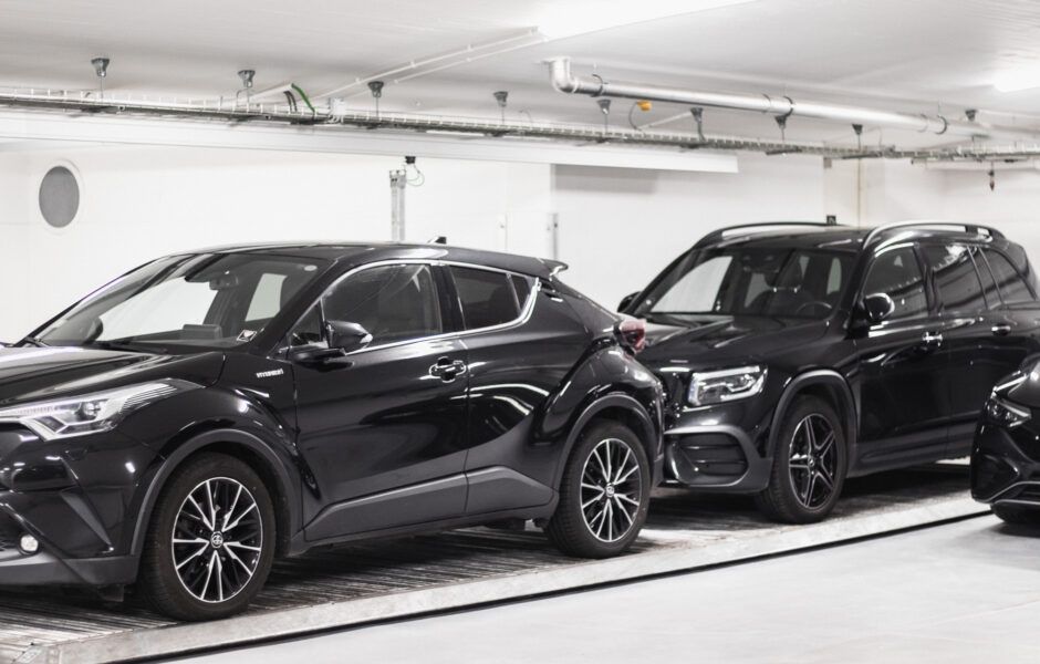 To sorte biler er parkeret ved siden af ​​hinanden i en parkeringskælder.