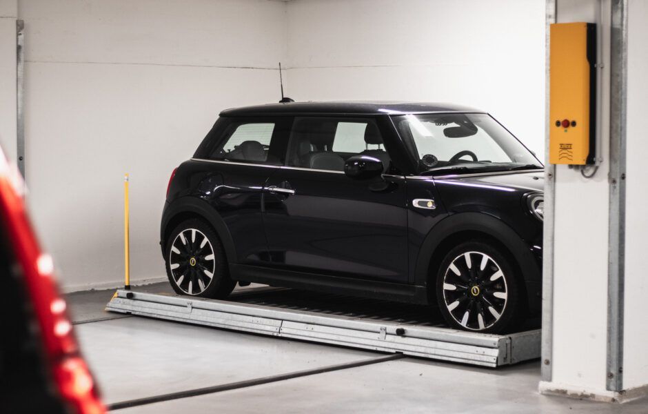 En sort mini bødker er parkeret på en elevator i en parkeringskælder.