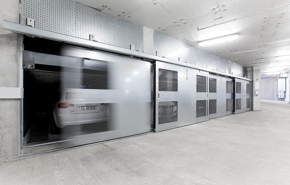 En bil kører gennem en glasskydedør i en parkeringskælder.