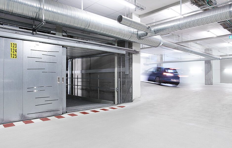 En bil kører gennem en skydedør i en parkeringskælder.
