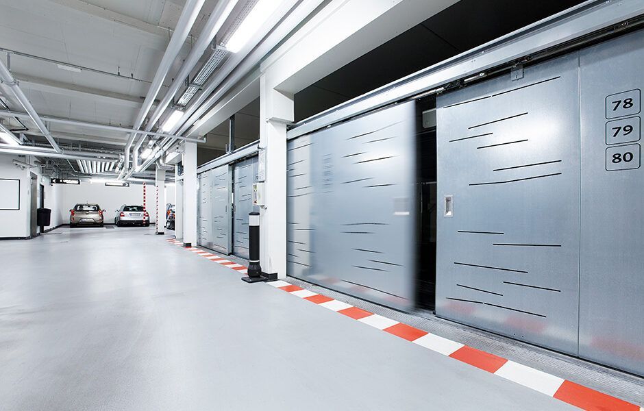 En parkeringskælder med skydedøre og biler parkeret i den.