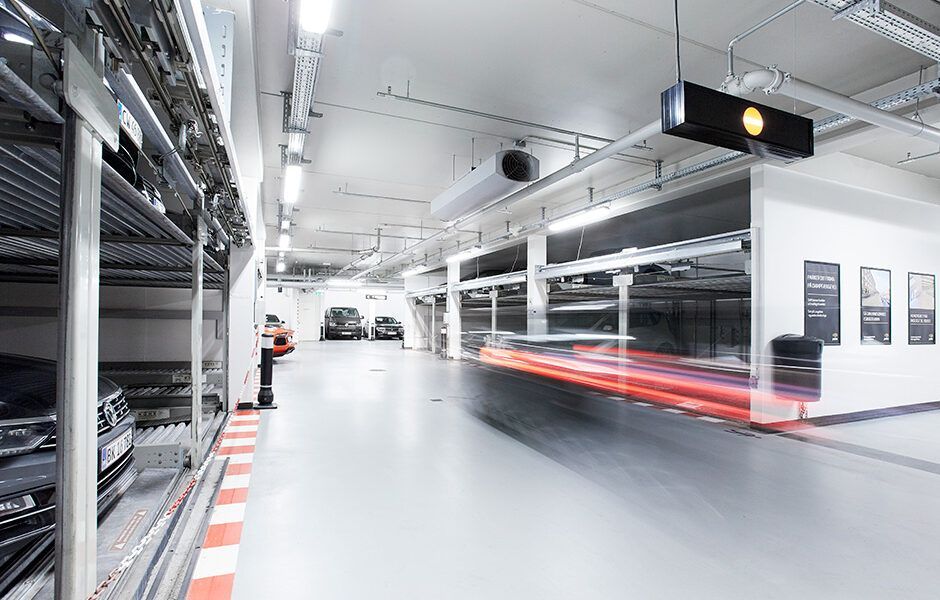 Et sløret billede af en parkeringskælder med biler parkeret i den.