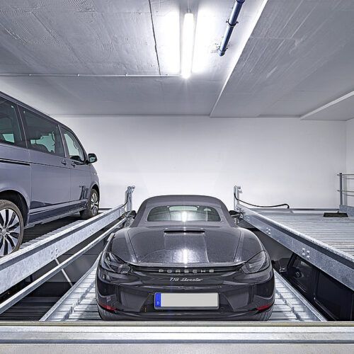 En bil er parkeret på et transportbånd i en parkeringskælder.