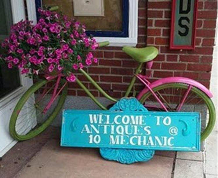 A bicycle with flowers and a sign that says welcome to antiques 10 mechanic