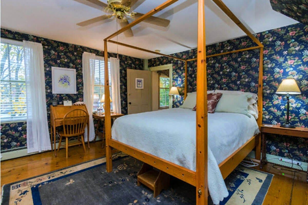 A bedroom with a four poster bed and a ceiling fan