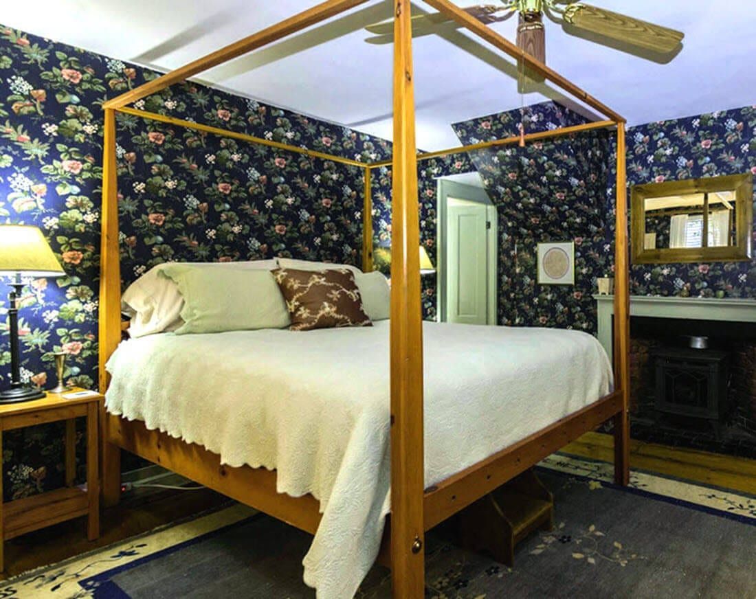 A bedroom with a four poster bed and a ceiling fan