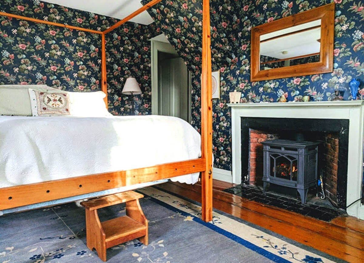 A bedroom with a four poster bed and a fireplace.