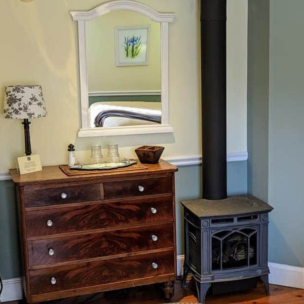 A bedroom with a dresser a lamp and a mirror