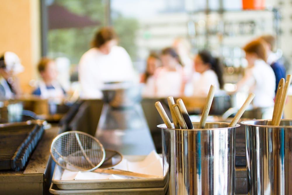 A bunch of utensils are sitting on a counter in a restaurant.