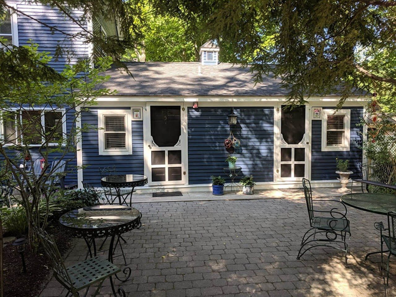 A blue house with a patio with tables and chairs in front of it.