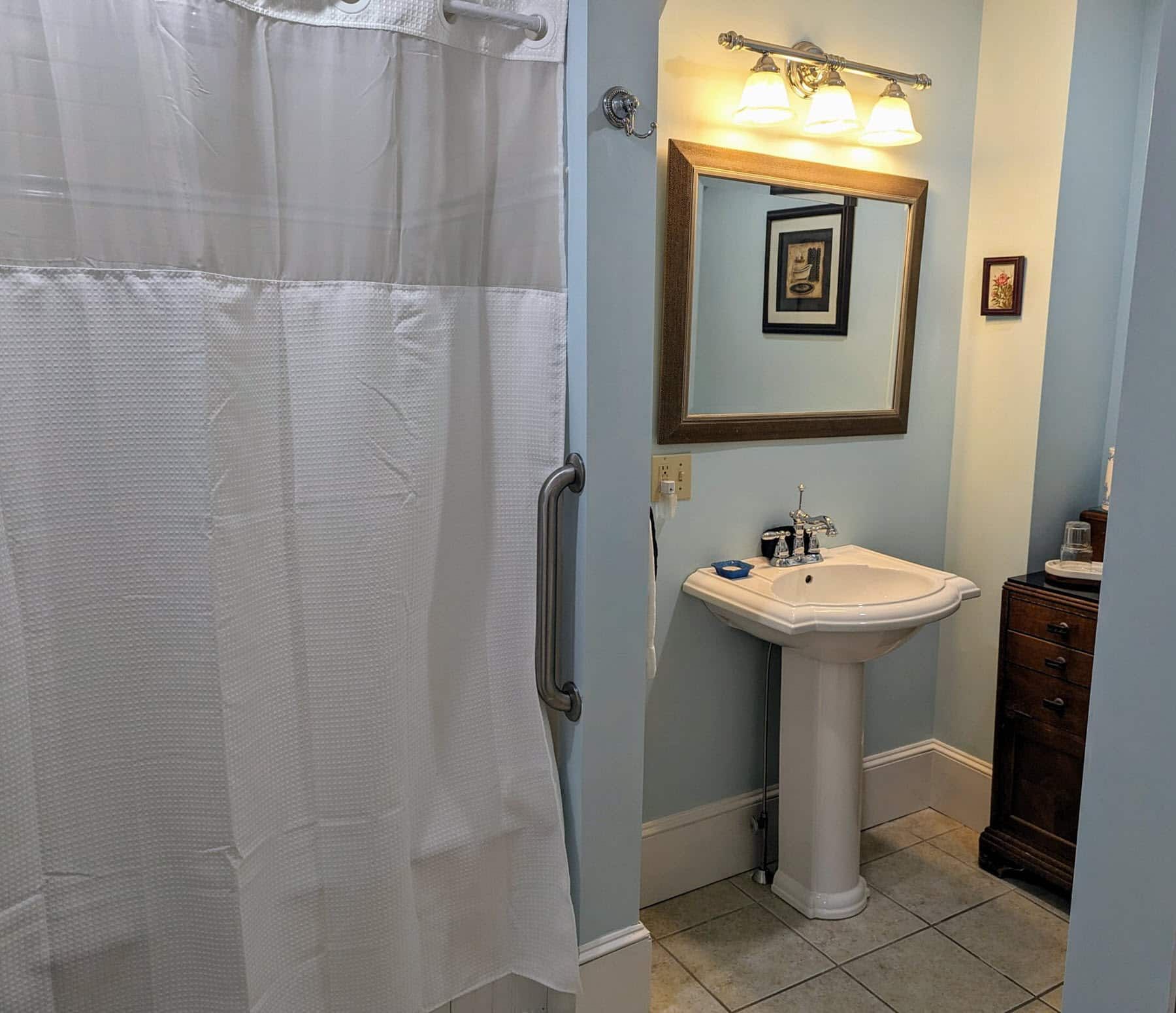 A bathroom with a sink , mirror and shower curtain