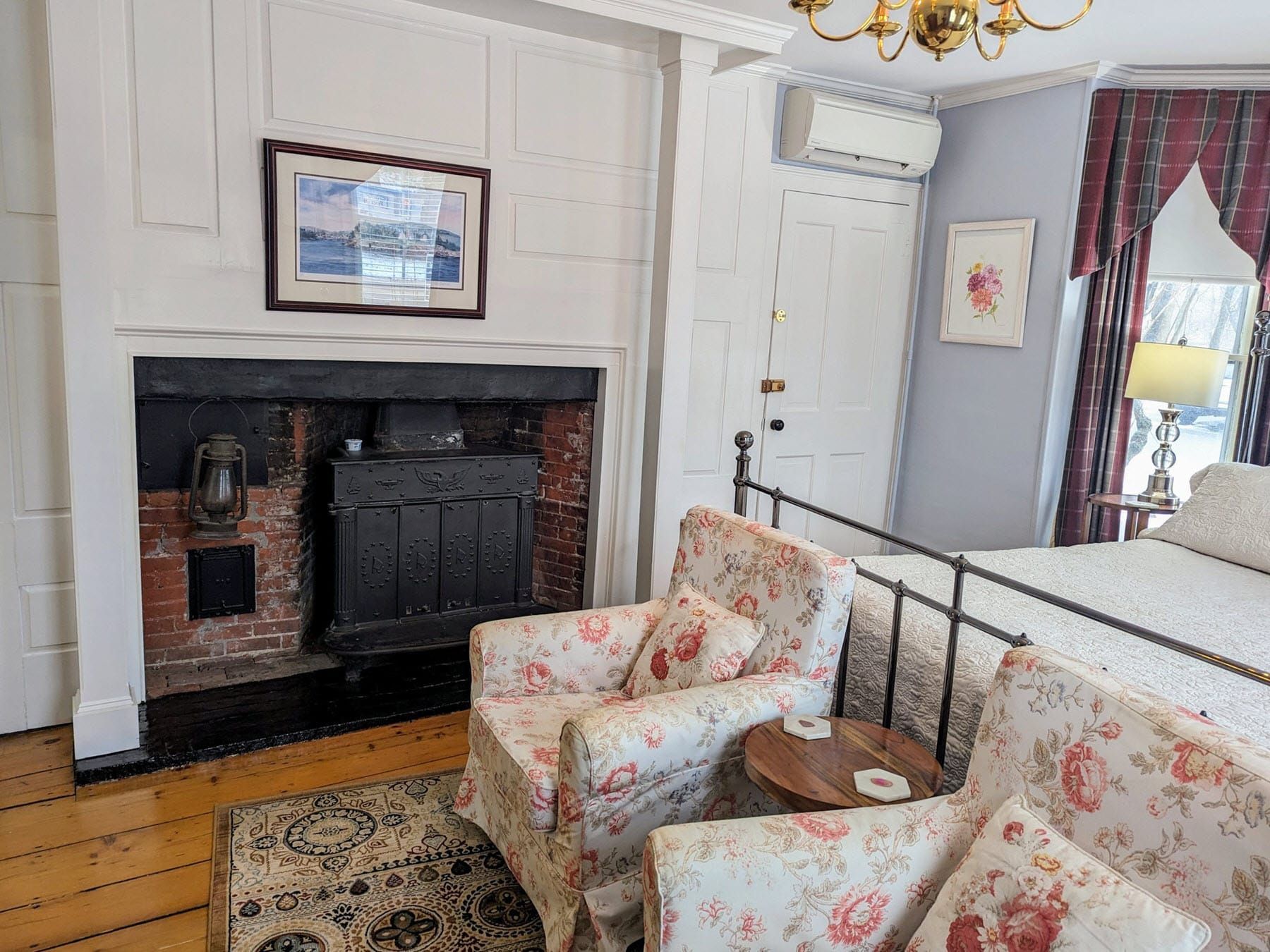 A bedroom with a fireplace , chairs and a bed.