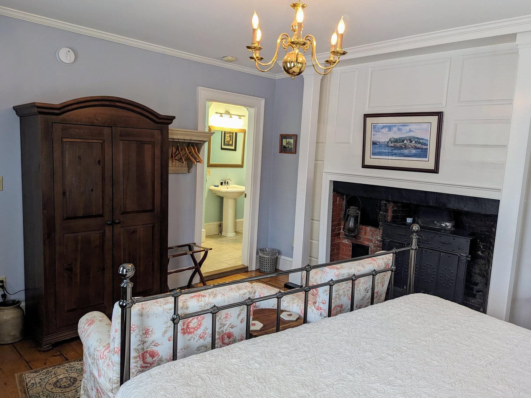 A bedroom with a king size bed , a fireplace , a wardrobe and a chandelier.