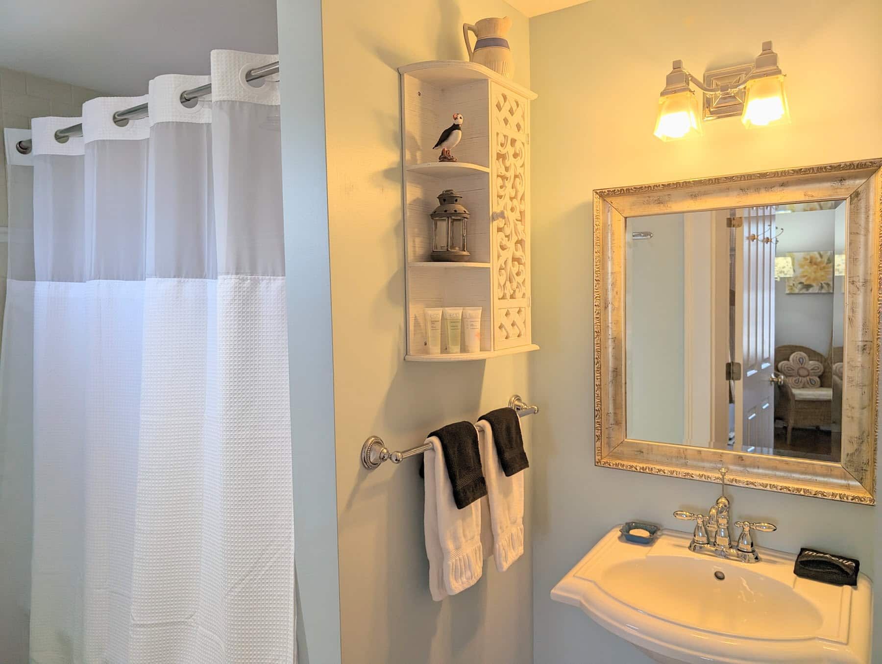A bathroom with a sink , mirror and shower curtain.