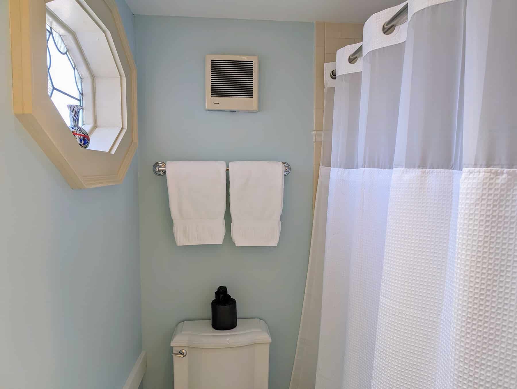 A bathroom with a toilet , shower curtain , and mirror.