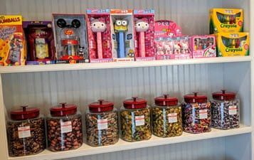 A shelf filled with jars of candy and toys.