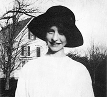 A black and white photo of a woman wearing a hat.
