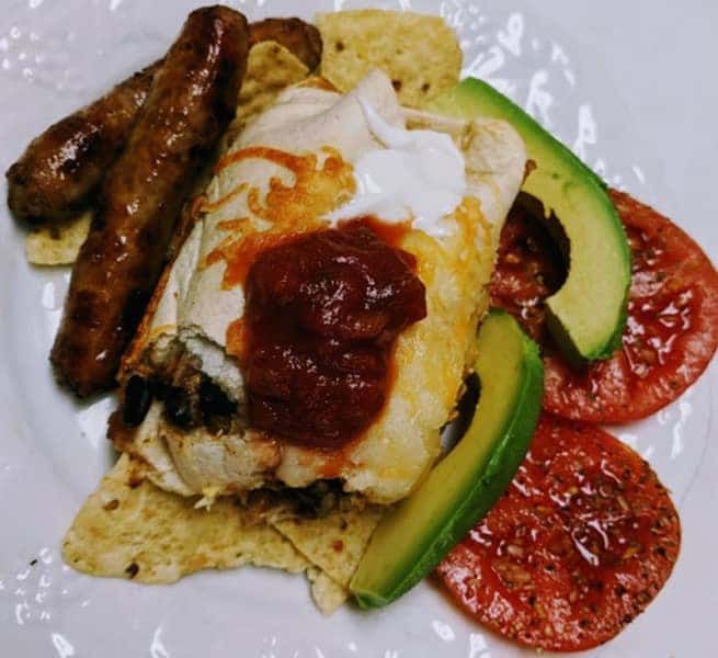 A plate of food with eggs avocado tomatoes and sausages
