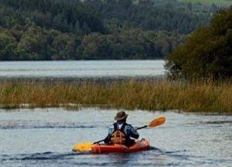 A person is paddling a kayak on a lake.
