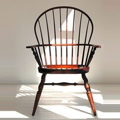 A wooden chair is sitting in front of a white wall