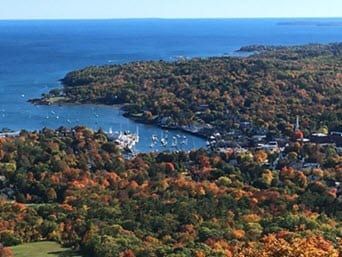 An aerial view of a small town surrounded by trees and a body of water.