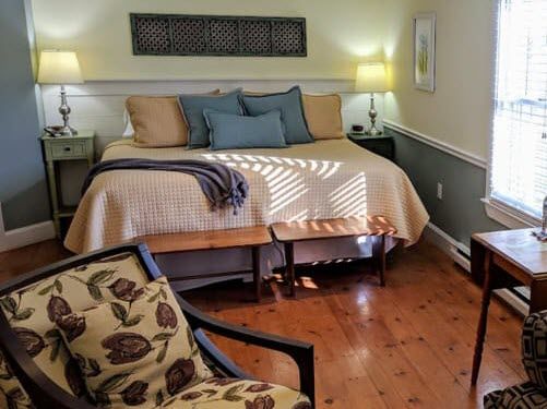 A bedroom with a bed , chair , table and window.