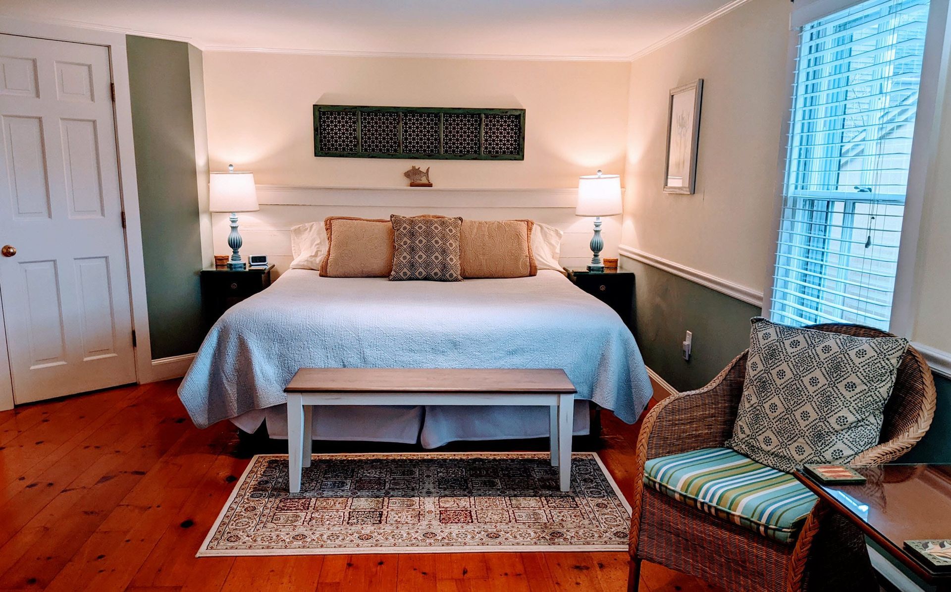 A bedroom with a king size bed , chair , bench and rug.