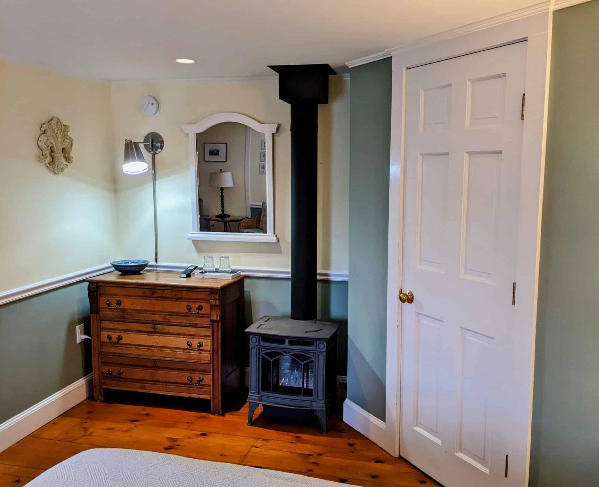 A bedroom with a wood stove and a mirror