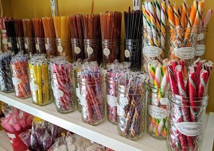 A shelf filled with jars of different colored candy canes.