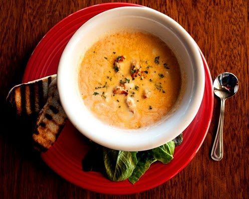 A bowl of soup on a red plate with a spoon